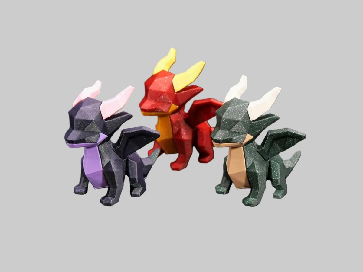 Three low-poly dragon figurines in different colors (dark gray with purple, red with yellow, and dark green with beige) displayed on a black background.