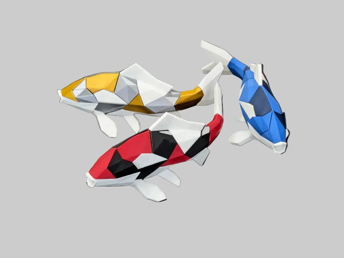 Three low-poly koi fish figurines in red, blue, and gold color schemes, arranged on a dark gray textured surface with the 'Thanabun Lab' logo at the bottom.