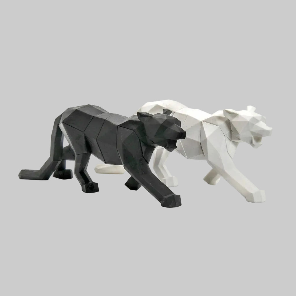 Two low-poly animal sculptures, shaped like panthers, shown on a clean light gray studio background. One sculpture is matte black and the other is matte white, positioned side by side.